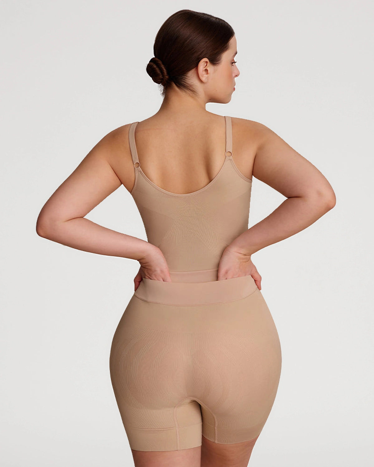 PLERIVA Seamless Full Body Sculpting Bodysuit in Nude, back view on model with hands on hips
